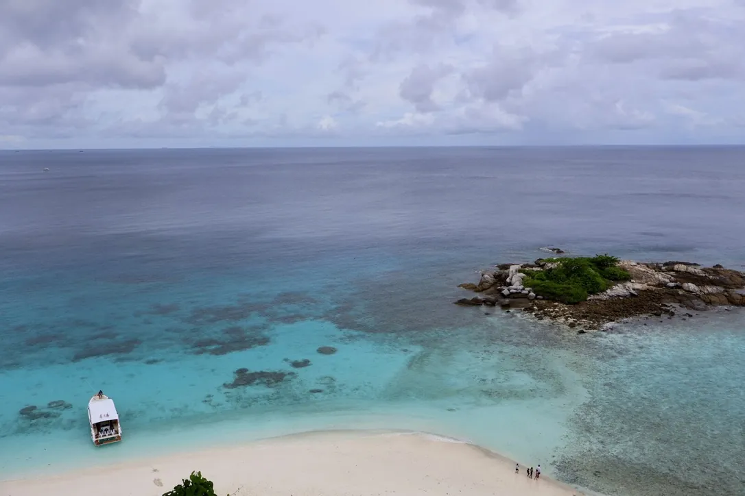 Vue aérienne d’une plage de sable blanc de Racha, le bateau au mouillage et un îlot rocheux