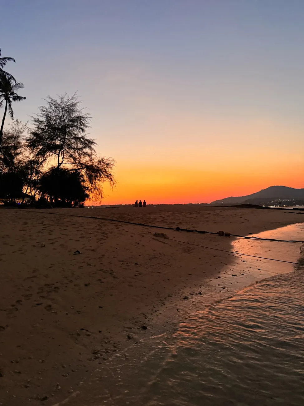 Plage de Phuket aux dernières lueurs du jour, silhouettes au bord de l’eau